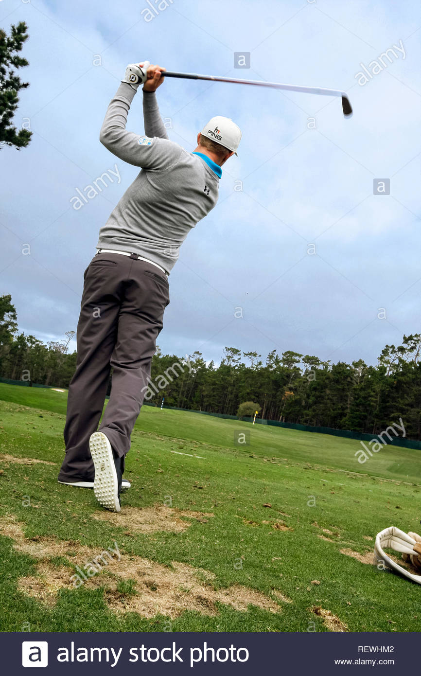 Man Swinging Golf Club On Course Viewed From Behind And Low