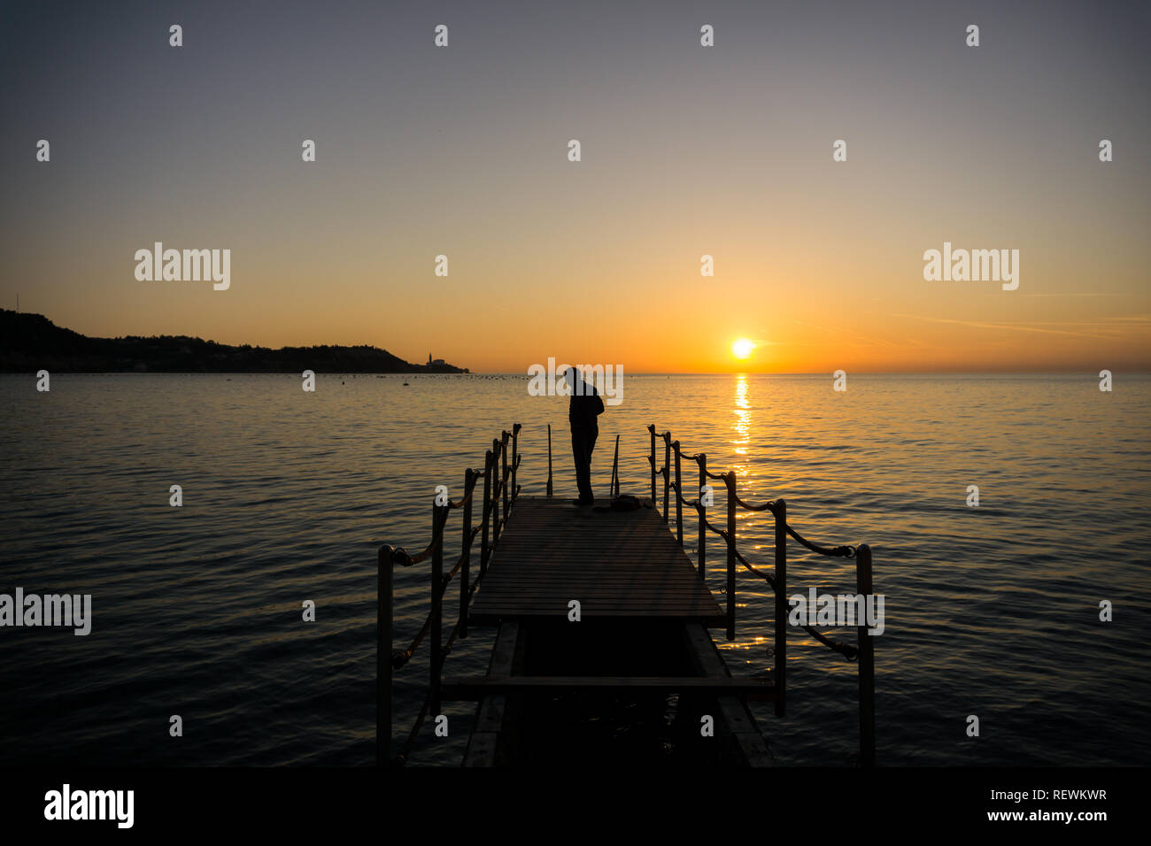 Silhouette of a man getting ready for swimming in seaside on sunset Stock Photo