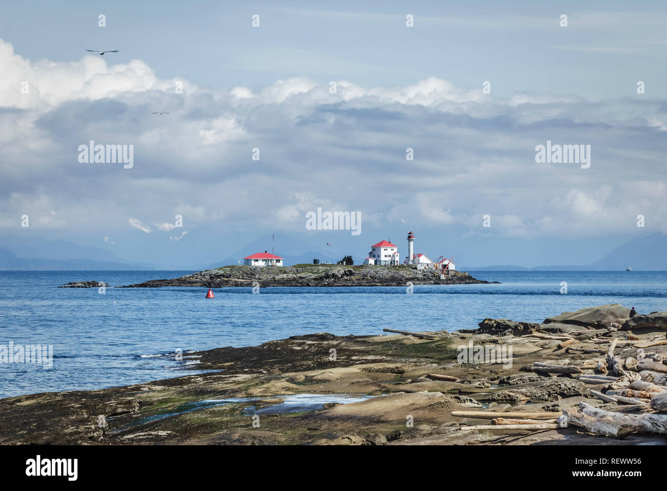 On a bright spring day, a view of Gabriola Island's sandstone beach with one person on it, and nearby Entrance Island Lighthouse (British Columbia). Stock Photo