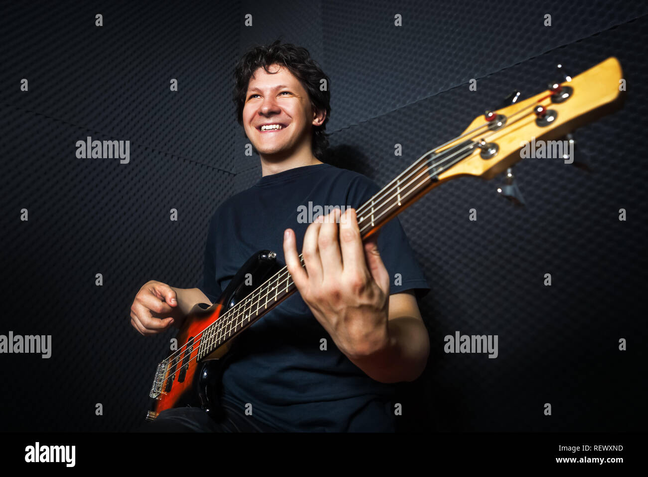 Handsome rock bass guitarist practicing in sound studio. Stock Photo
