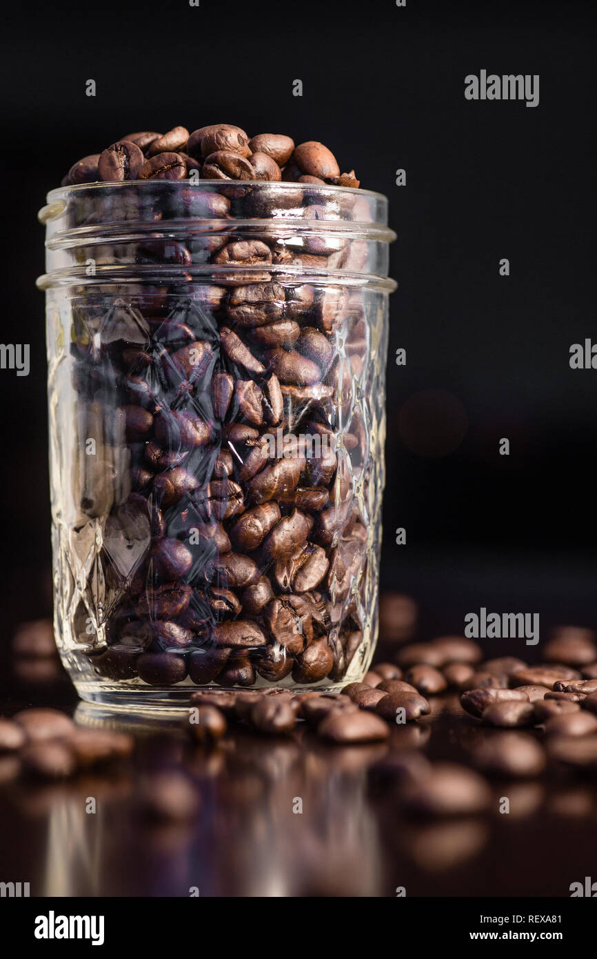 Coffee beans in a glass jar and spilled on the table Stock Photo