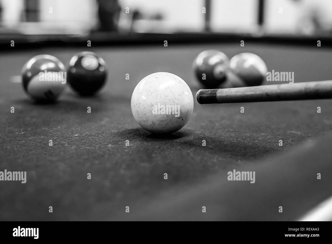 Cue ball about to be hit on a pool table in black and white Stock Photo