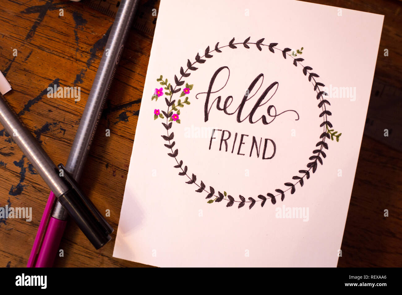 Pens and a Card that says 'hello friend' on a desk Stock Photo