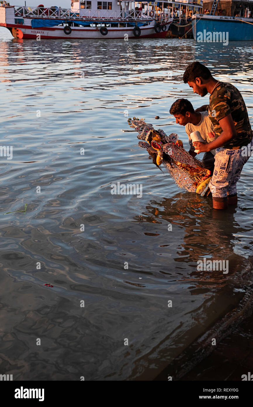 a statue of a goddess is placed in the Ganges River as part of a Hindu ...