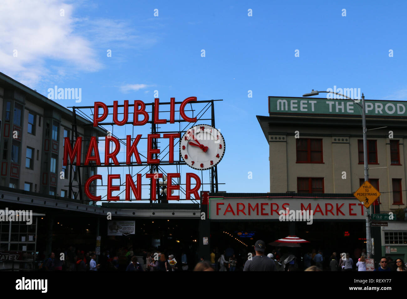 Iconic sign and entrance to the Pike Place Market in Seattle, Washington on a sunny day with blue sky and partial clouds, shoppers passing by Stock Photo