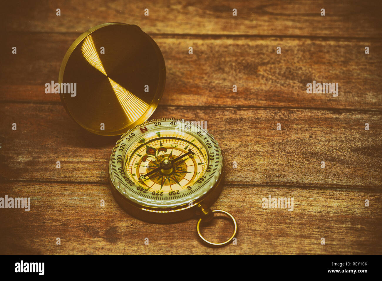 An old compass on a brown wooden table Stock Photo