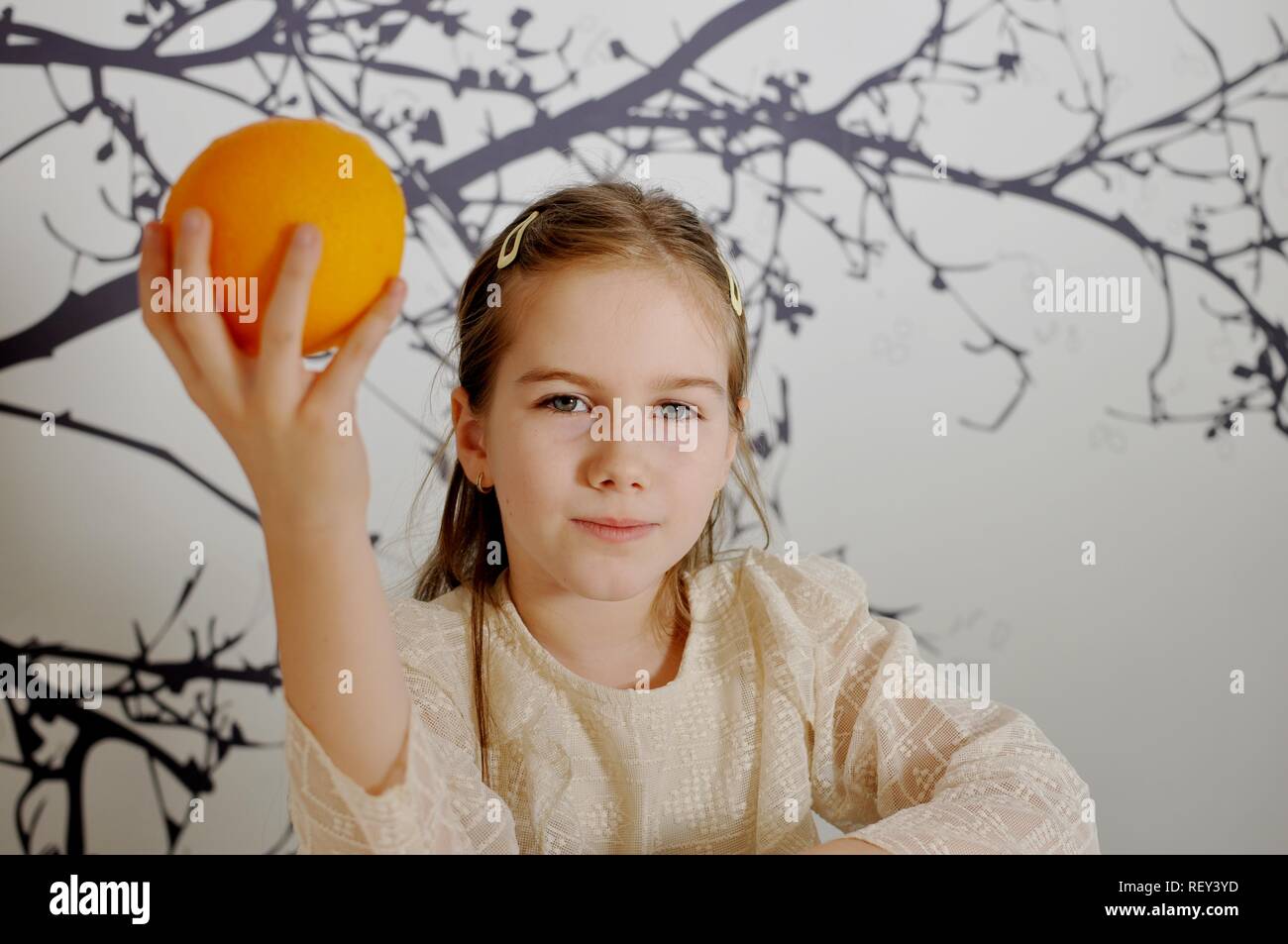 White Caucasian girl (child, kid) showing an orange in his hand Stock Photo