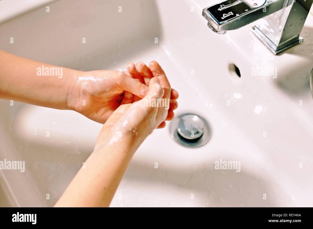 Concept of Caucasian white child hands washing with soap above the washbasin. Stock Photo