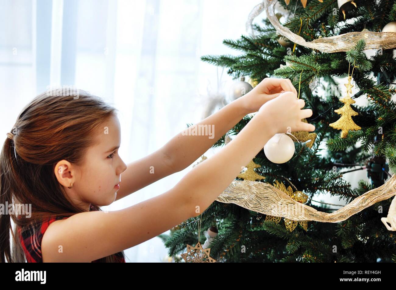 White Caucasian child (kid), girl, decorating the Christmas tree Stock Photo