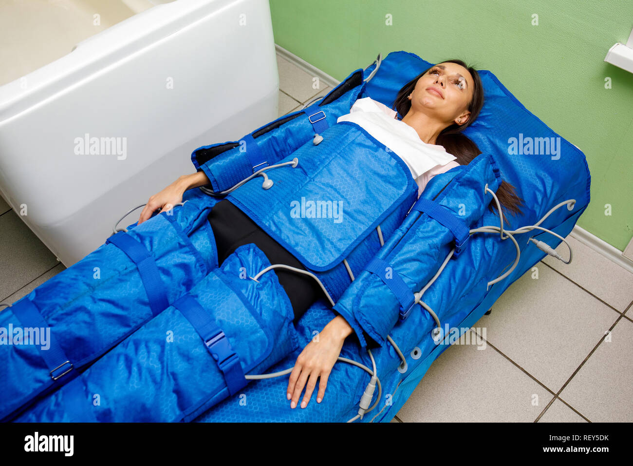 Woman in pressotherapy suit lying down having pressure therapy for
