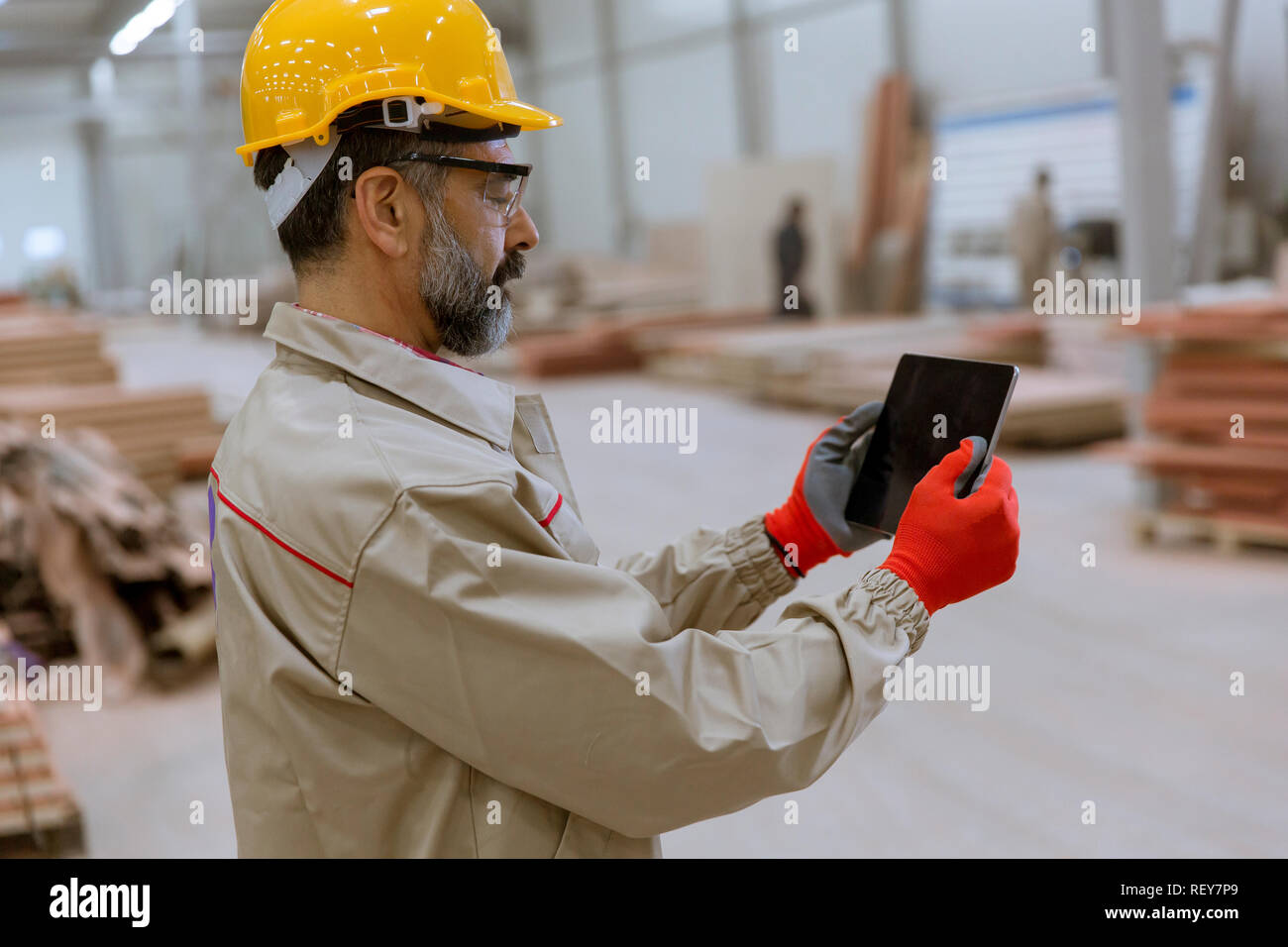 Handosme senior engineer with helmet controlling works in factory with digital tablet Stock Photo