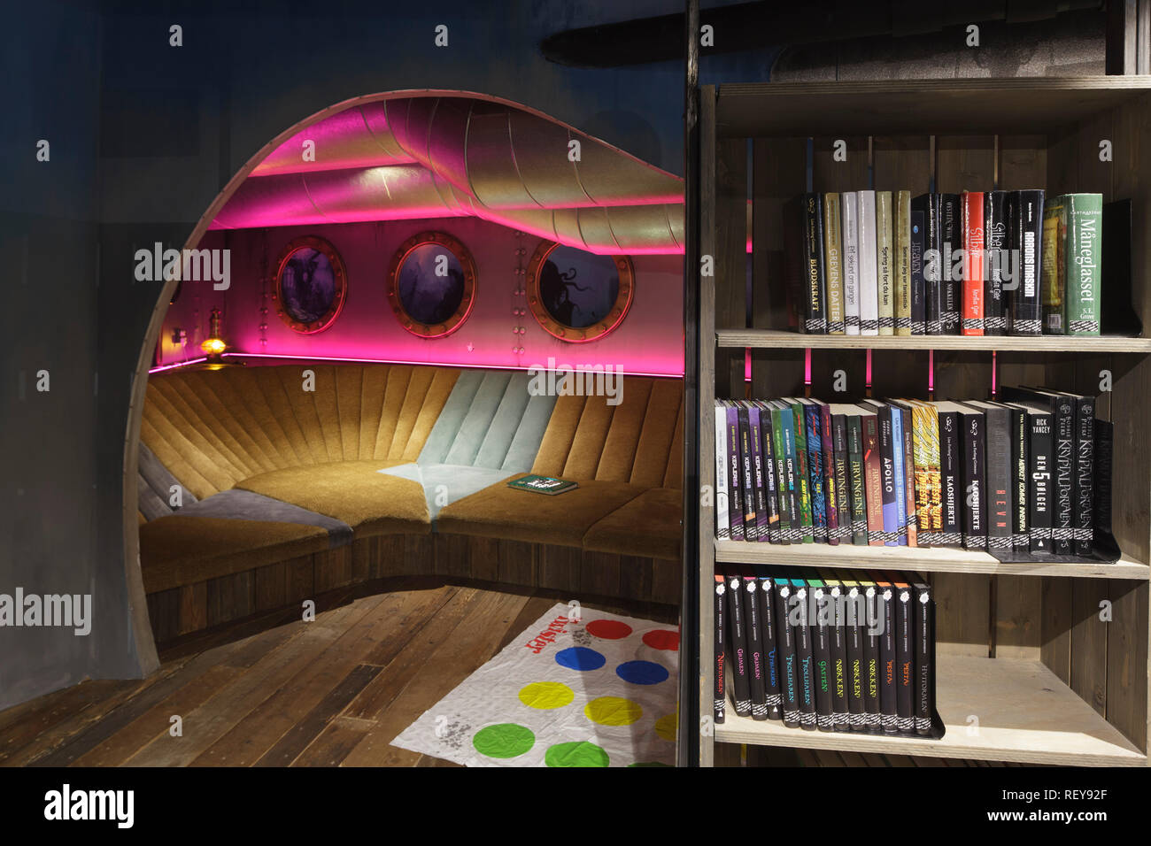 Submarine-themed seating area, with overhead portholes and pink lighting and bookshelf to right. Deichman Biblo Toyen Children's Library, Oslo, Norway Stock Photo