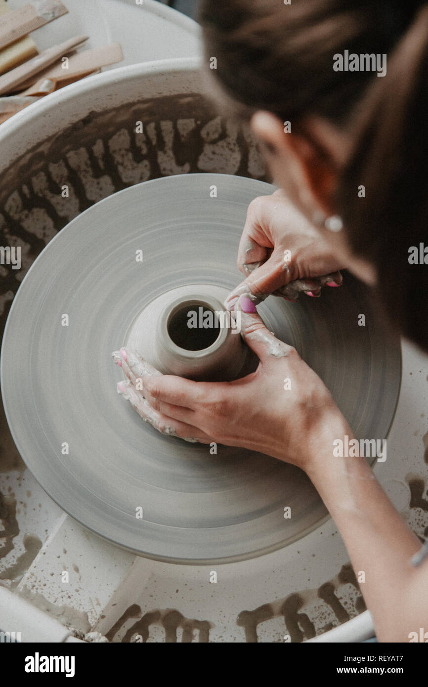 Creating a jar or vase of white clay closeup. Woman hands making clay