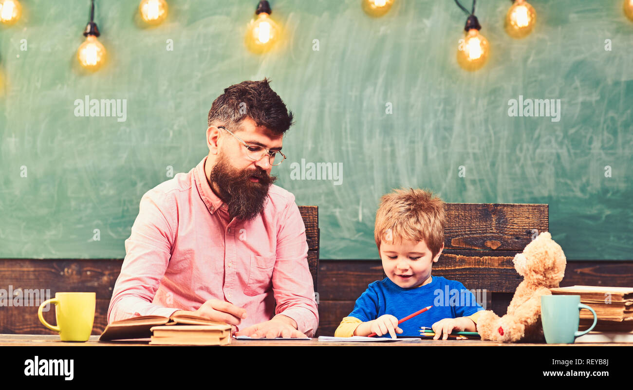 Teacher and small kid writing letters in copybook. Cute boy drawing a picture with colorful pencils. Art lesson at kindergarten Stock Photo