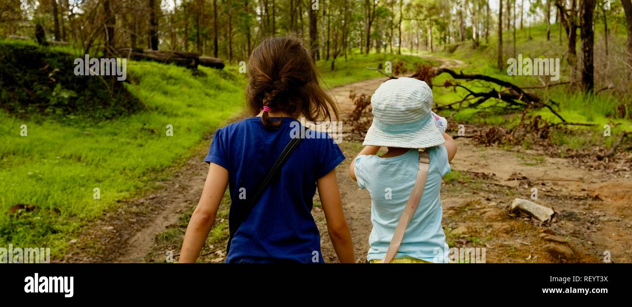 Two children walking along a four wheel drive track through a forest, Mia Mia State Forest, Queensland, Australia Stock Photo