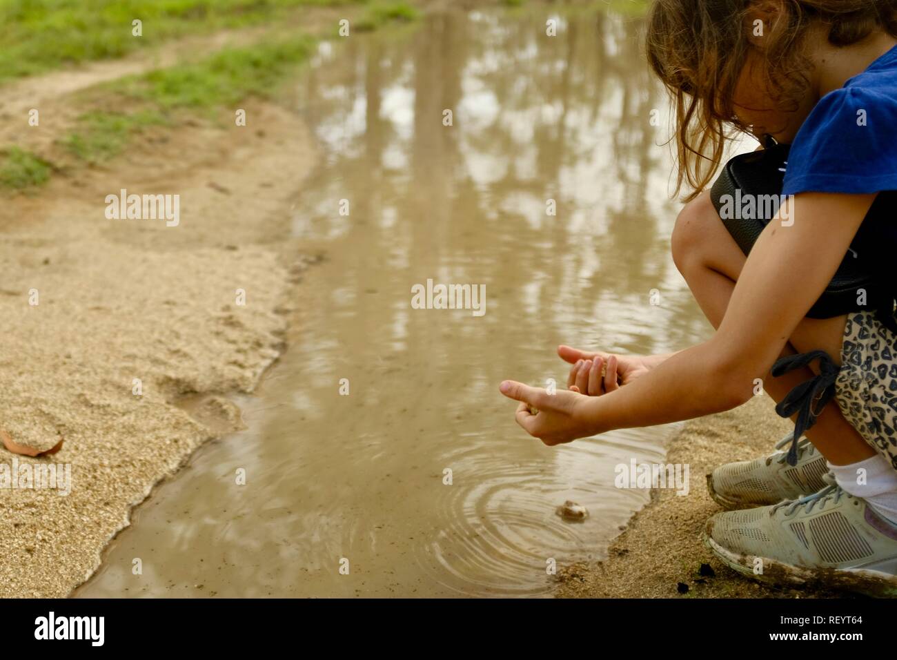 A young girl playing in a muddy puddle on a four wheel drive track through a forest, Mia Mia State Forest, Queensland, Australia Stock Photo