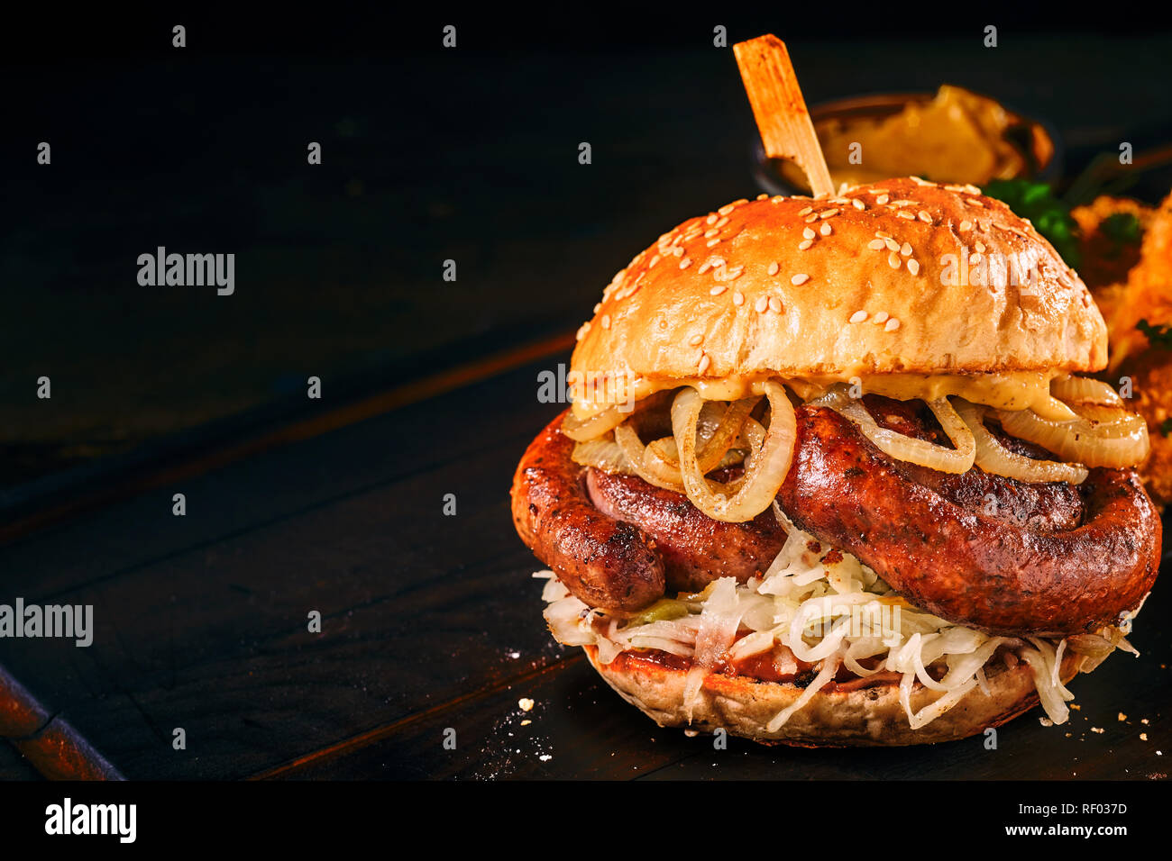 Spicy traditional German bratwurst burger on a sesame bun over a dark