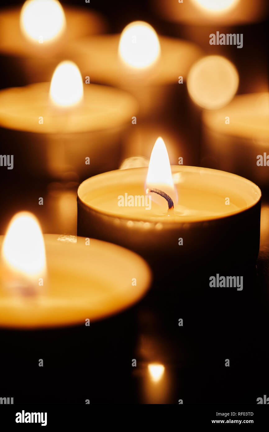 Burning tea light candles in darkness conceptual of a votive offering