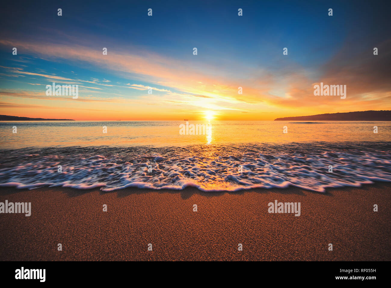 Beautiful sunrise over the sea. Waves washing sandy beach Stock Photo ...
