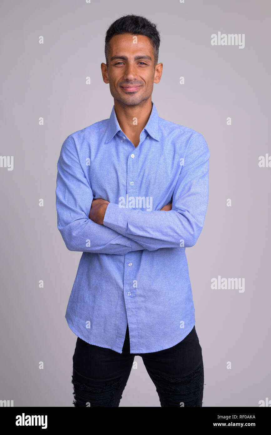 Portrait of young happy Persian businessman smiling with arms crossed ...