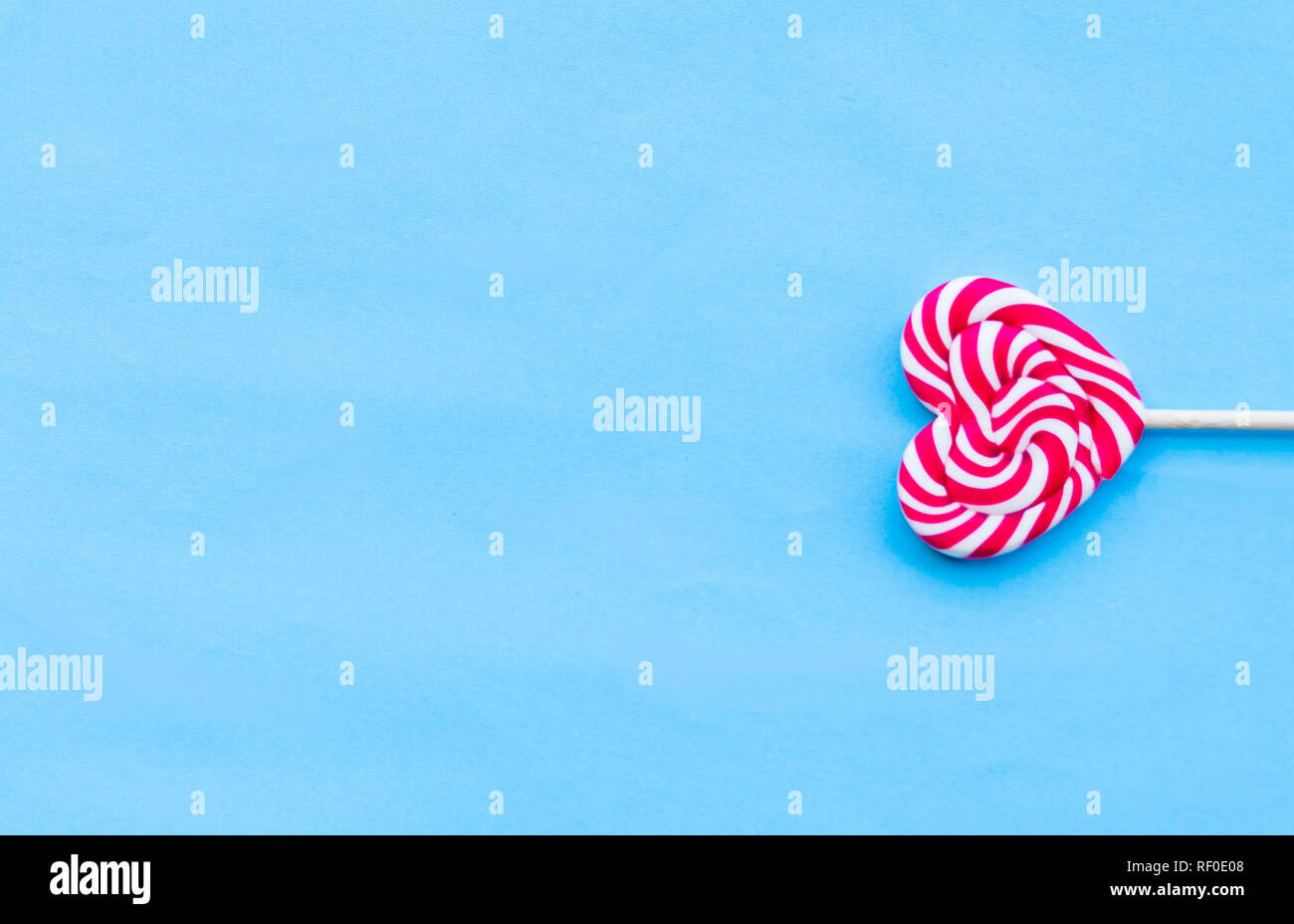 Single Valentines Day heart-shaped lollipop blue background. Love ...
