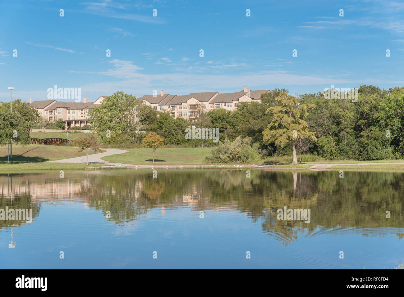 Beautiful urban park with lake reflection and apartment complex in