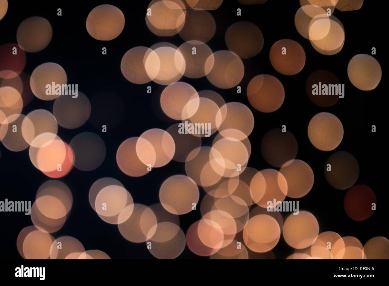 Yellow and orange Christmas tree bokeh on black background of defocused