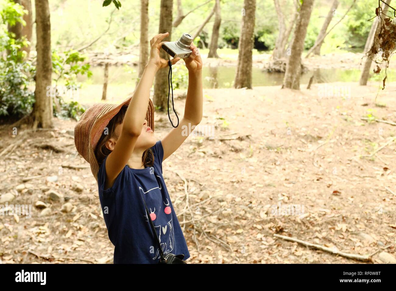 A young girl using a camera to take a photo in nature, Mia Mia State Forest, Queensland, Australia Stock Photo