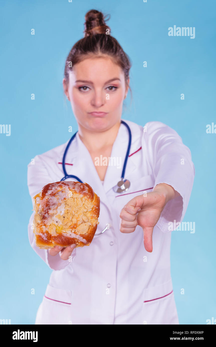 Dietitian nutritionist holding sweet roll bun showing thumb down