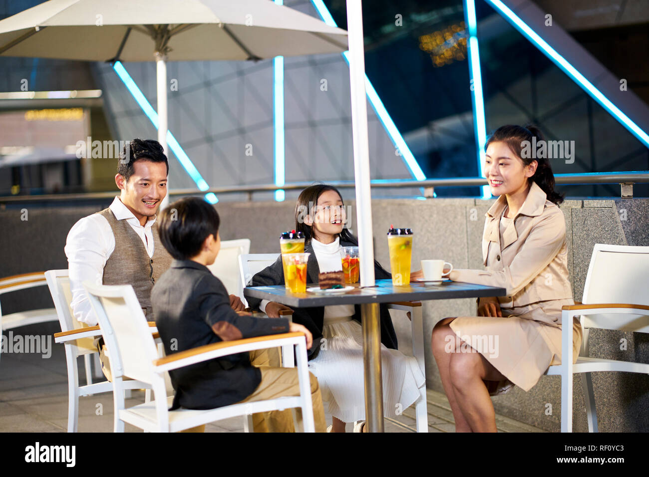 happy asian family with two children relaxing talking having drinks and desserts at an outdoor coffee place. Stock Photo