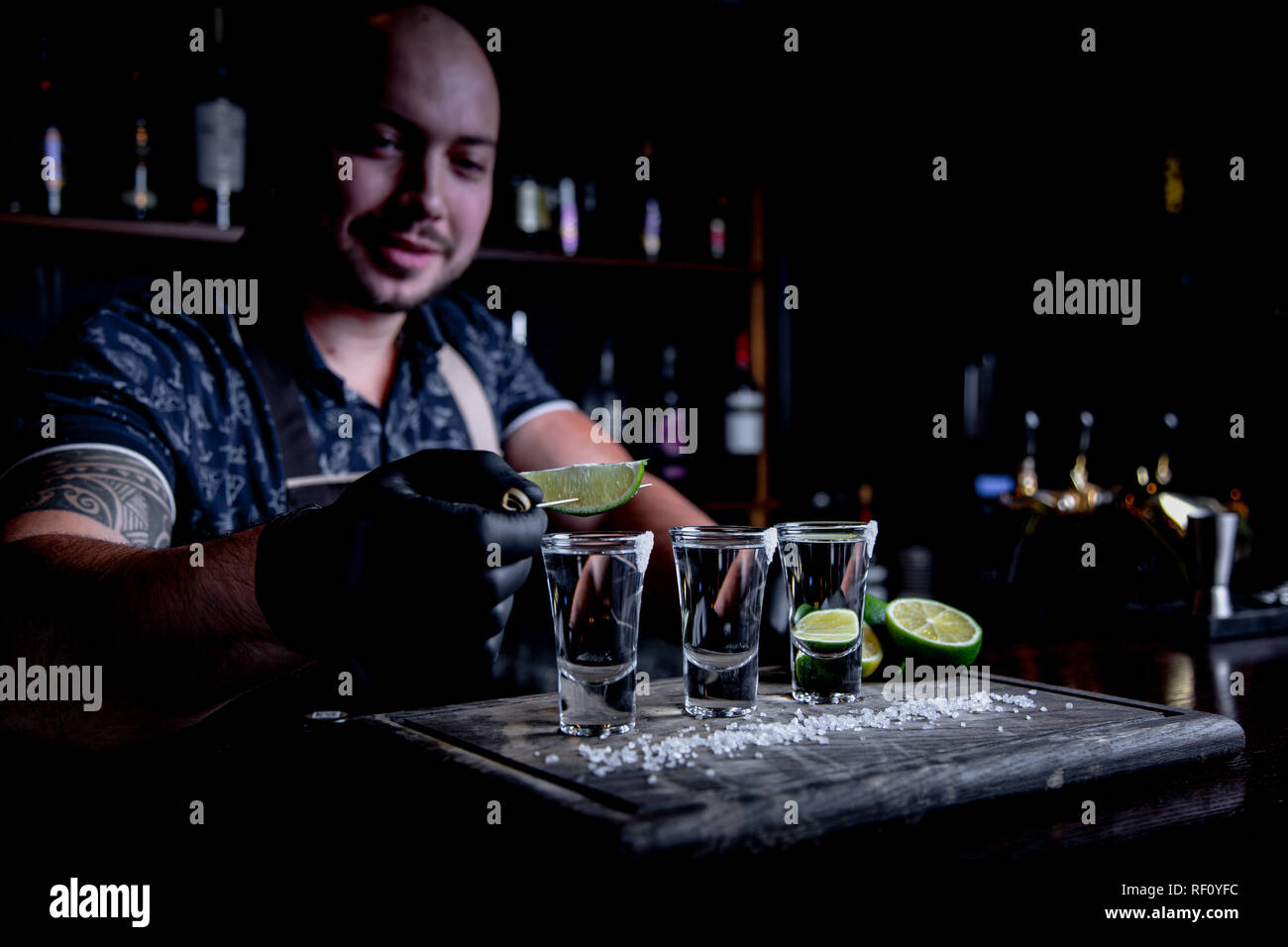 aperitif with friends in the bar, three glasses of alcohol with lime and salt for decoration. Tequila shots, selective focus Stock Photo