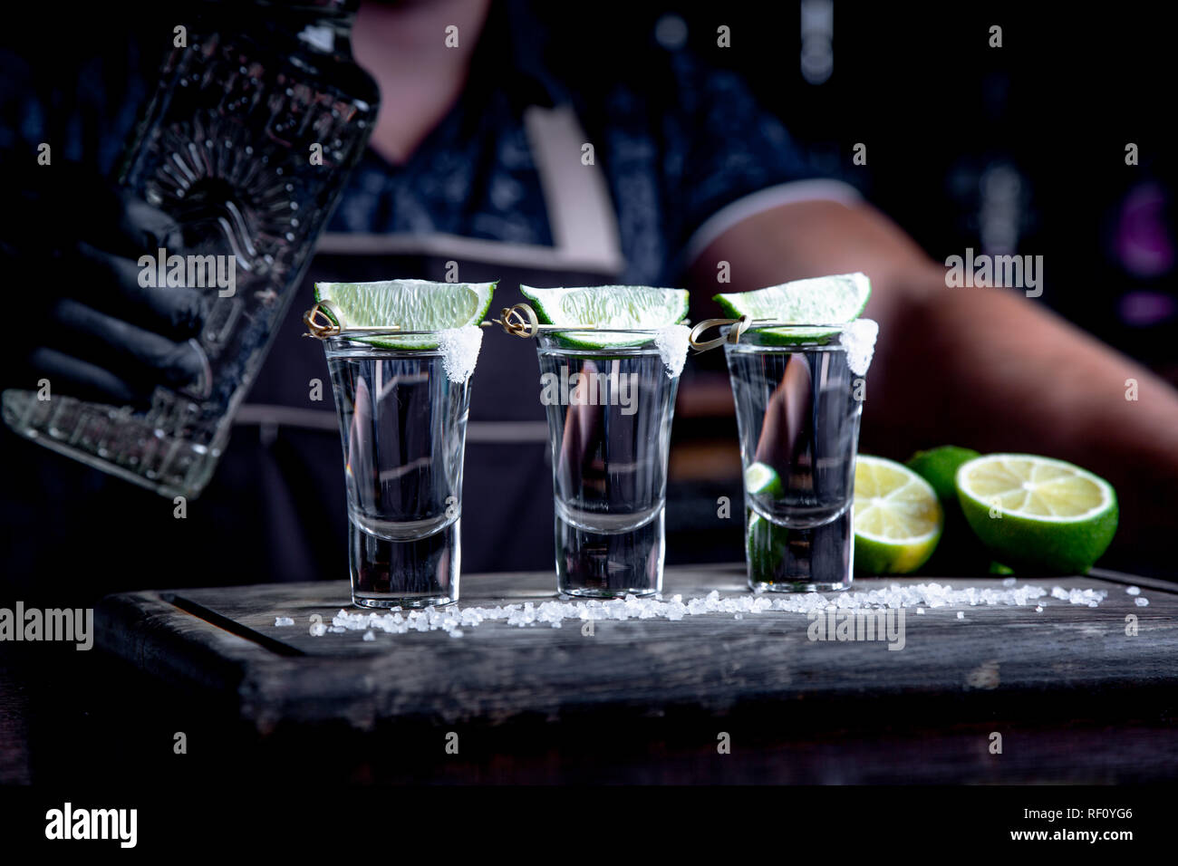 aperitif with friends in the bar, three glasses of alcohol with lime and salt for decoration. Tequila shots, selective focus Stock Photo