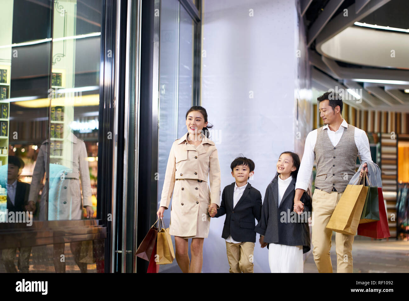 happy asian family with two children walking in shopping mall Stock Photo