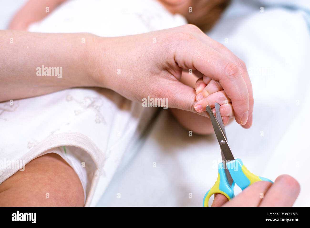 Close up of mother cutting babies nails with scissors. Nursing a child