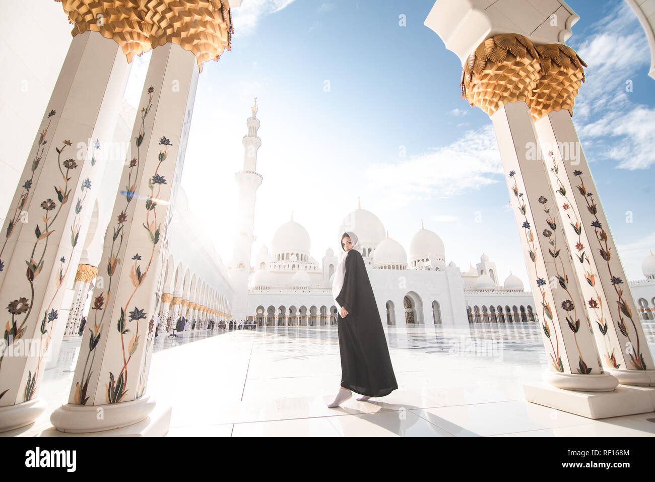 Traveling by Unated Arabic Emirates. Woman in traditional abaya standing in the Sheikh Zayed Grand Mosque, famous Abu Dhabi sightseeing. Stock Photo