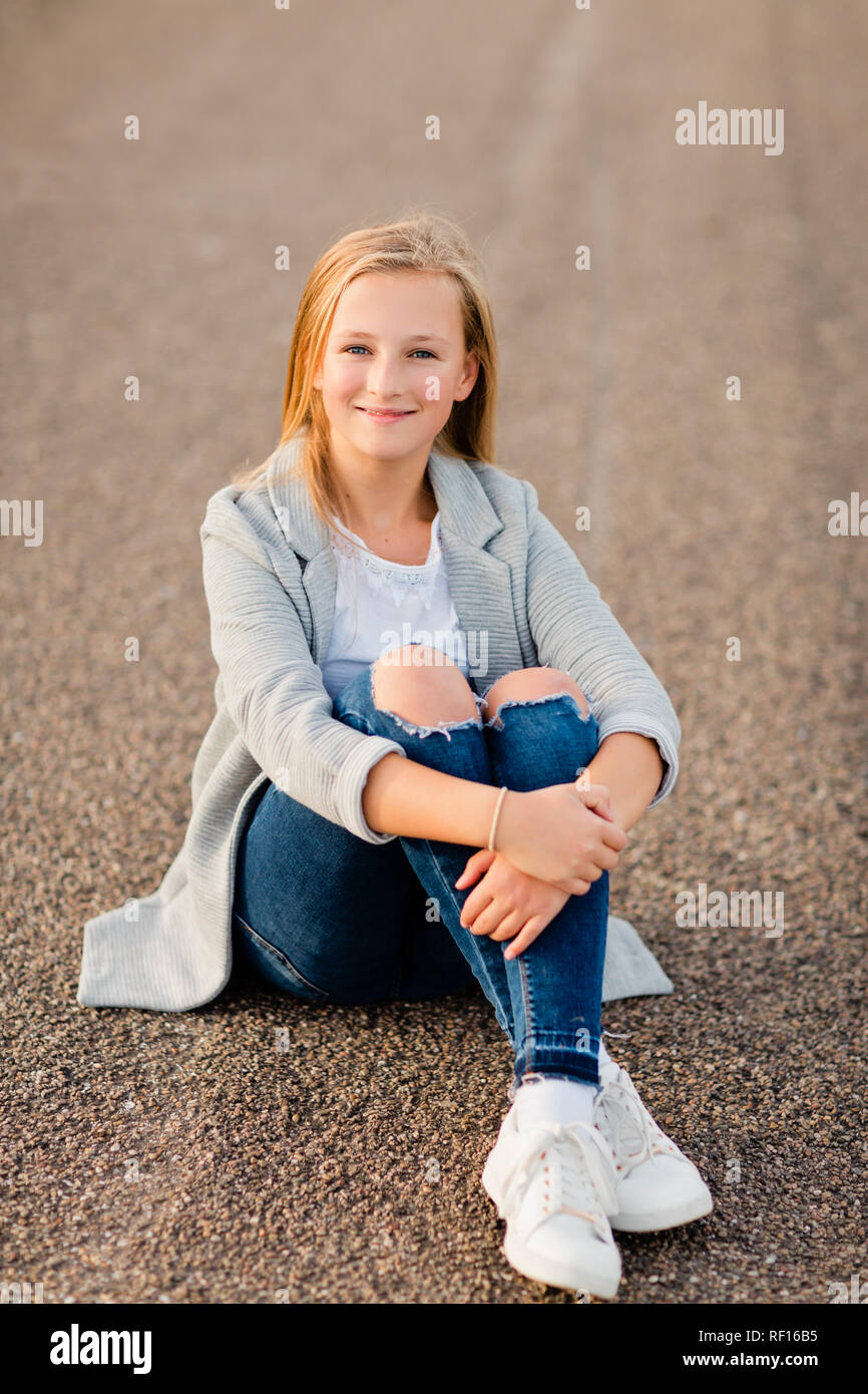 Portrait of smiling girl sitting on ground Stock Photo - Alamy