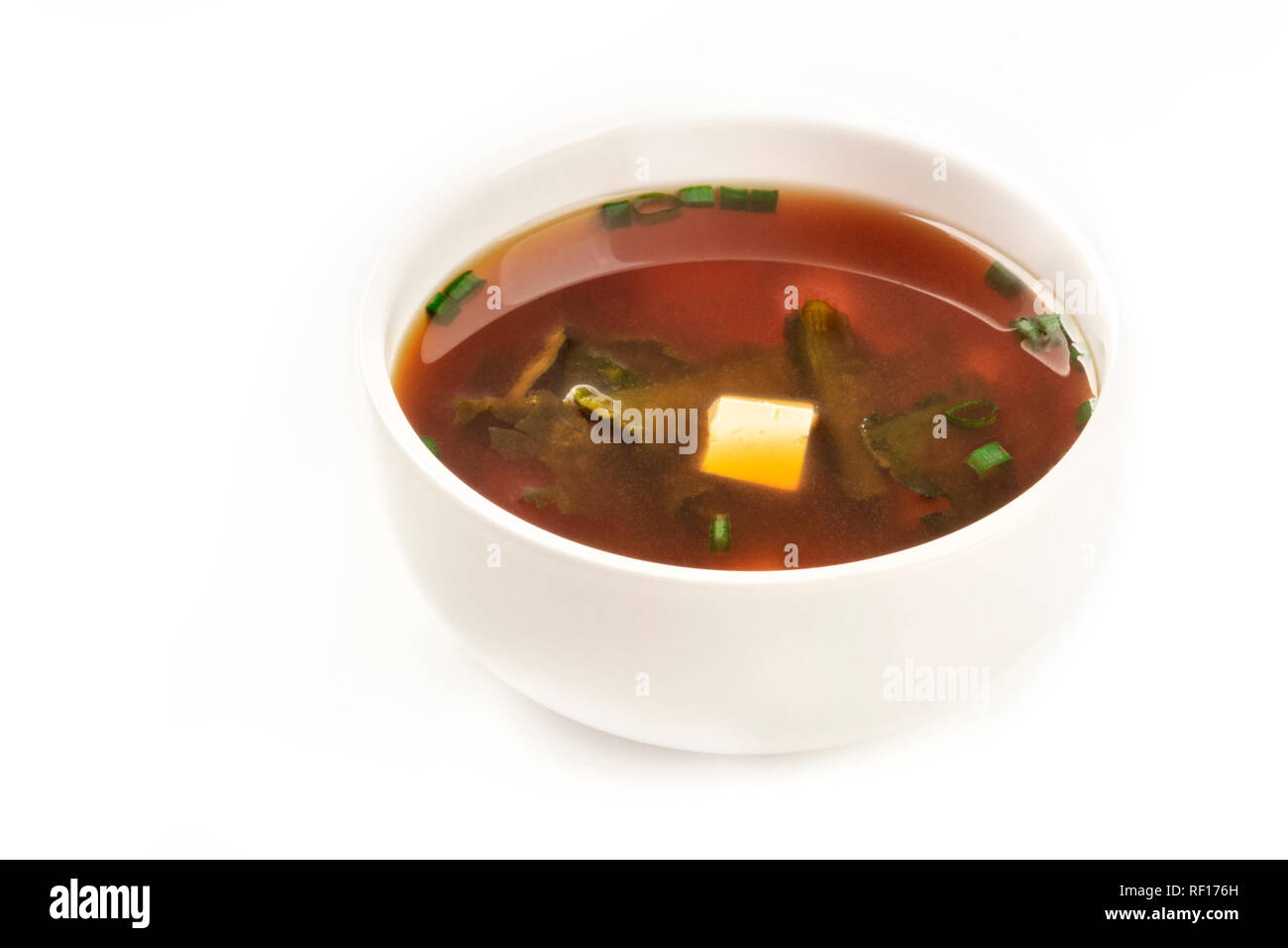 A photo of a bowl of miso soup with tofu, scallions, and wakame algae