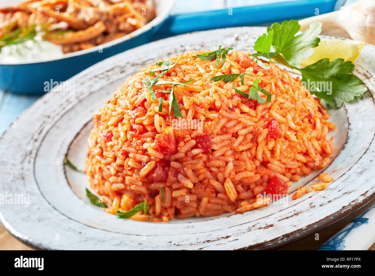 Healthy nutritious plate of Greek tomato rice or pilaf topped with fresh chopped coriander and served on a rustic earthenware plate Stock Photo