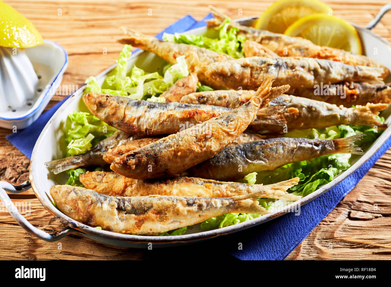 Dish of battered fried sardines, pilchards or anchovies on a bed of fresh lettuce for a healthy Greek regional meal Stock Photo