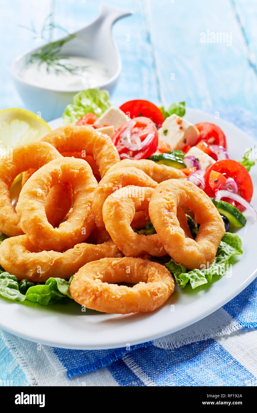 Crispy golden deep fried squid rings in batter on a bed of lettuce with