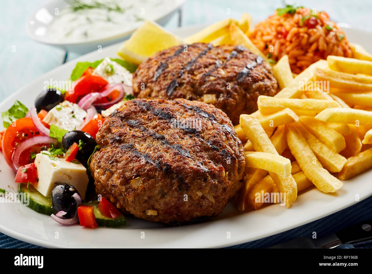 Traditional bifteki, minced beef meat balls, with fresh Greek salad