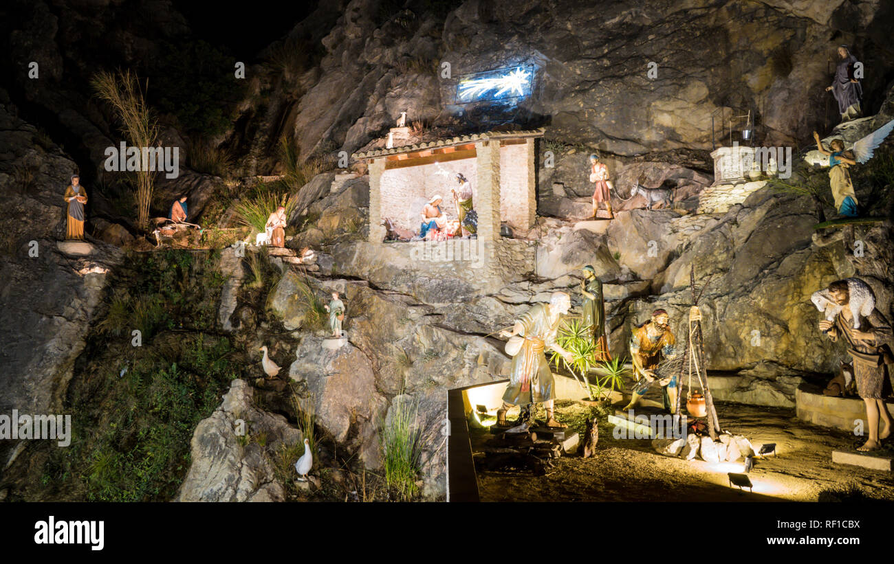 The most beautiful Christian nativity scene in a cave on a river in Jijona, Spain with Maria, Jose, Jesus figures between palms during Christmas Stock Photo