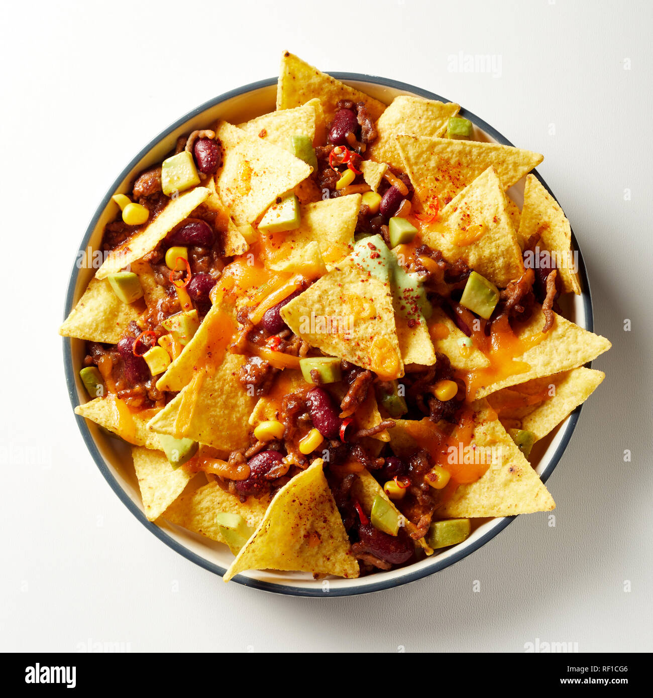 Mexican chili con carne with nachos topped with cheese and baked in an oven  viewed from overhead in a dish over white Stock Photo - Alamy