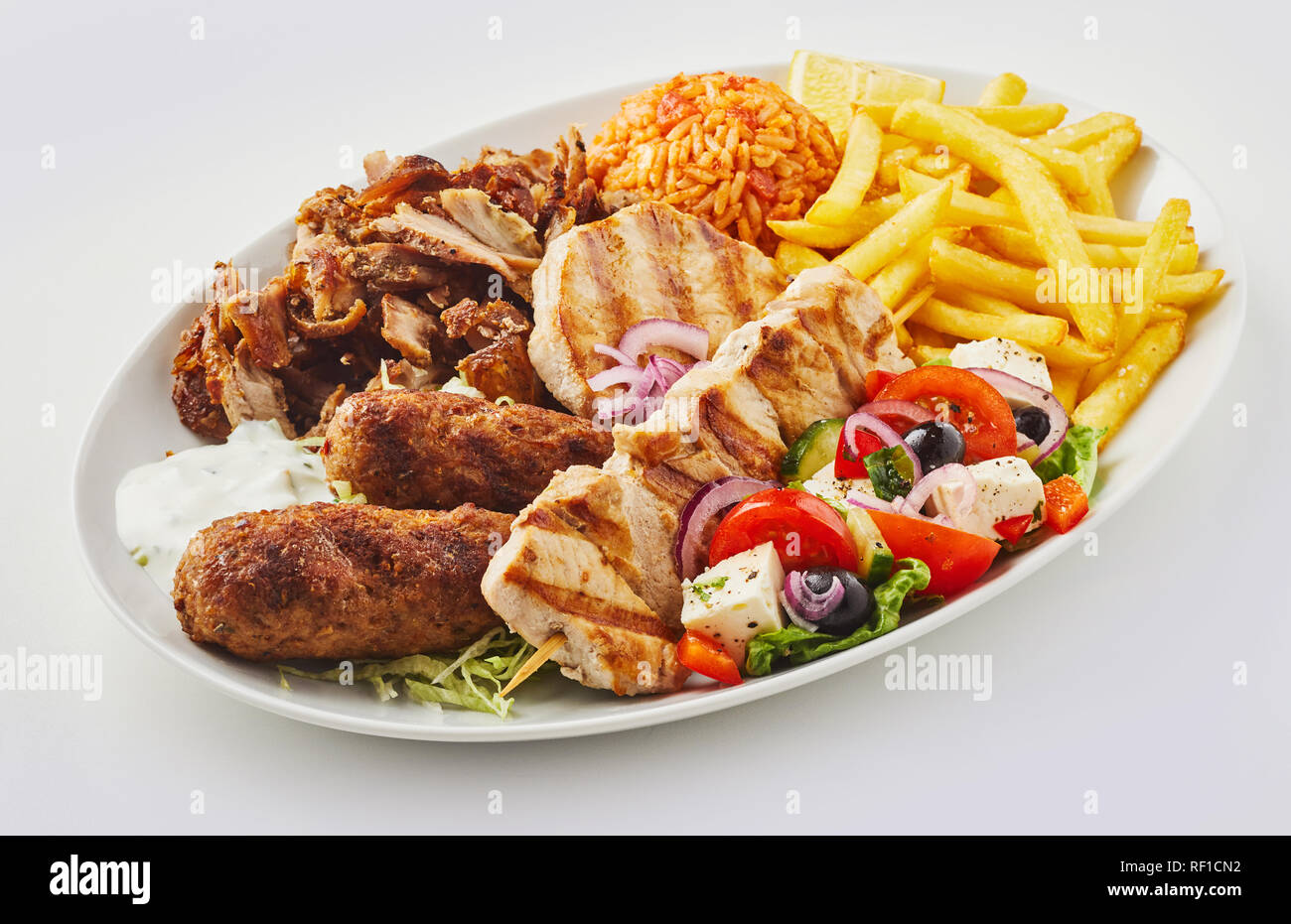 Greek mixed grill platter with salad, domatorizo and French Fries and a selection of souvlaki, souzuki steak and grilled pork skewers Stock Photo