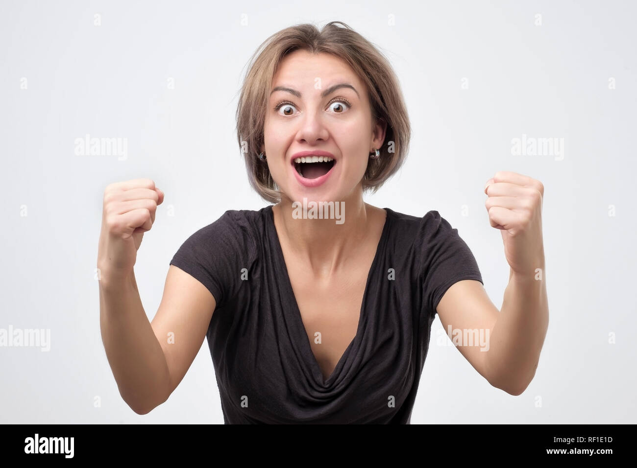 Young woman with raised hands shouting and celebrating success Stock ...