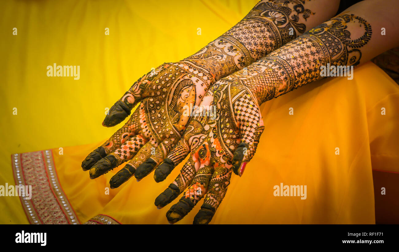Henna painting, mehendi on bride's hands with the yellow dress background.  Wedding preparation in India Stock Photo - Alamy