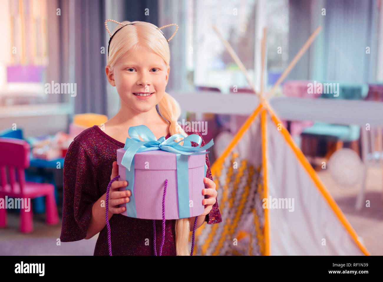 Positive delighted blonde girl holding box with present Stock Photo Alamy