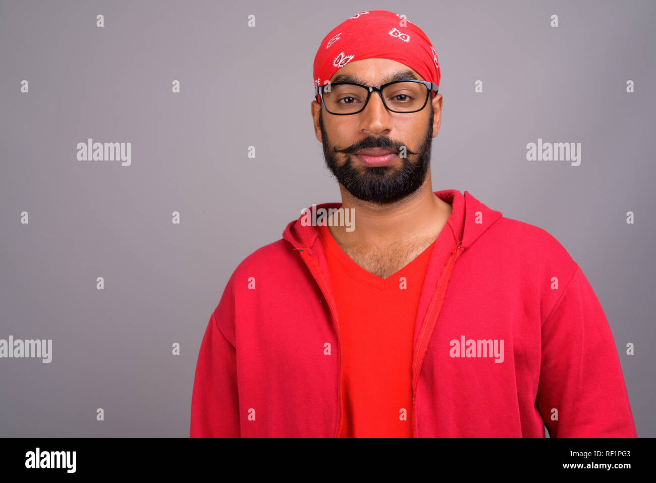 Portrait of young handsome Indian man wearing red shirt Stock Photo