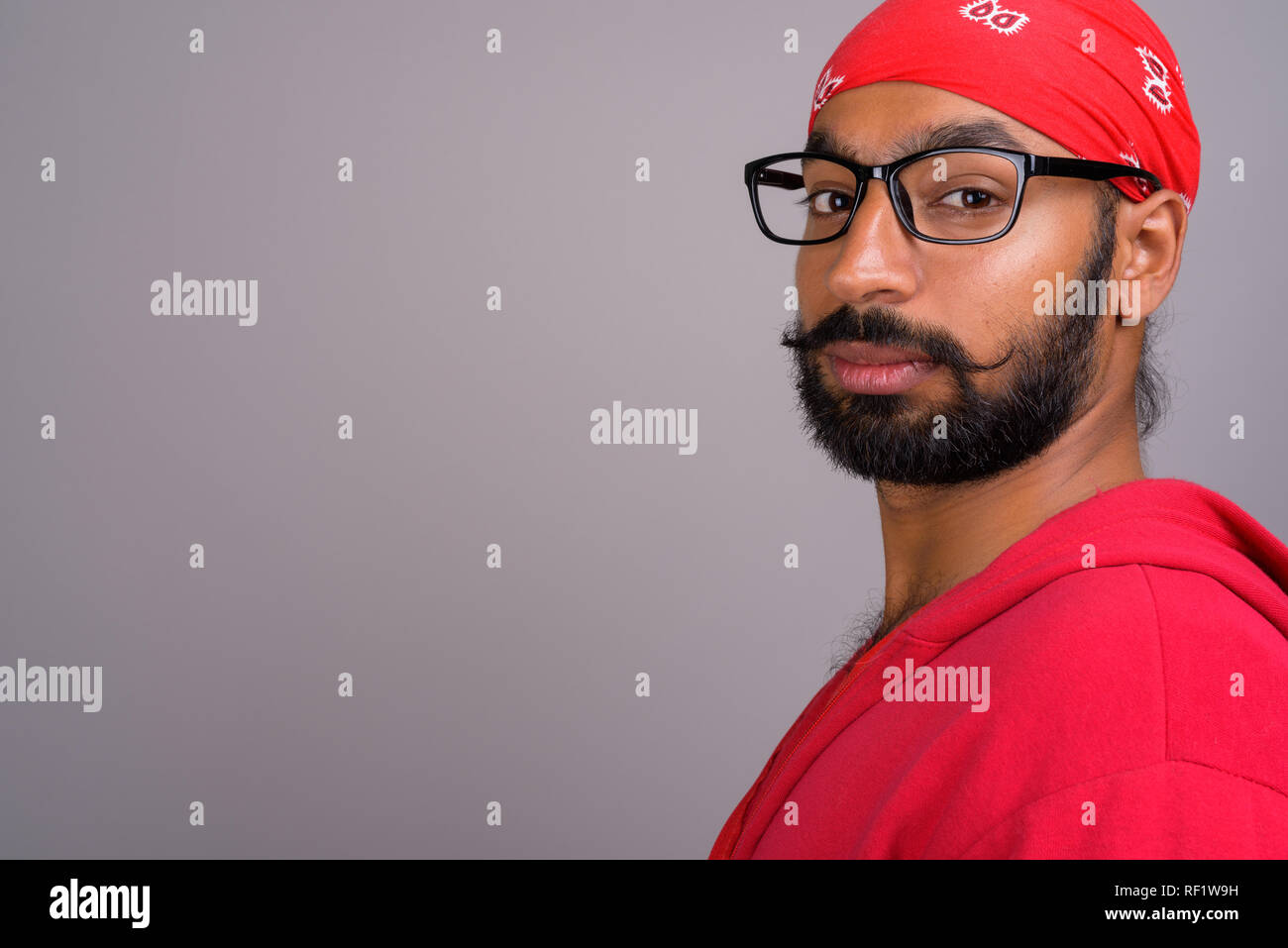 Portrait of young handsome Indian man wearing red shirt Stock Photo