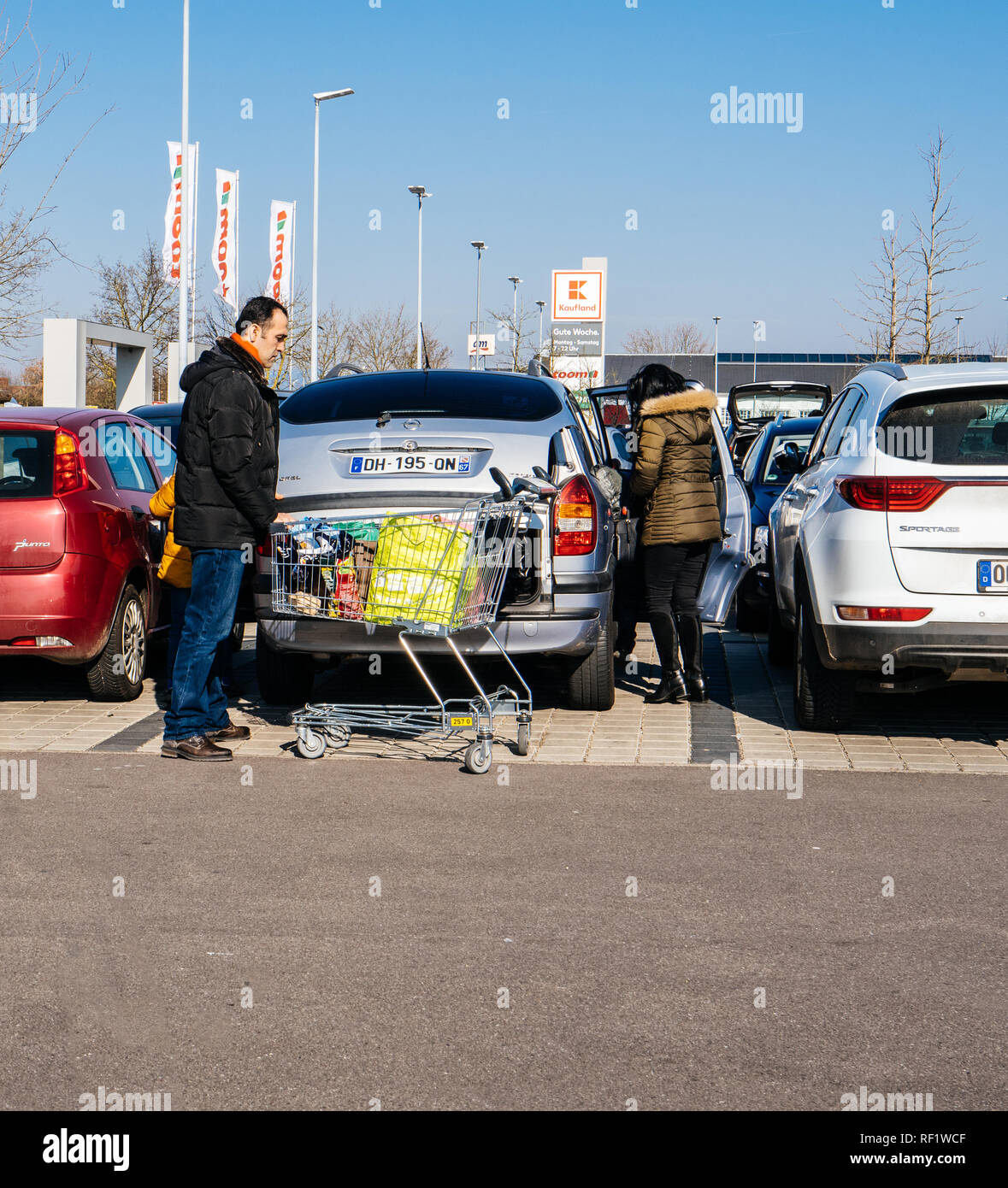 KARLSRUHE, GERMANY - FEB 24, 2018: Eastern ethnicity family couple loading groceries in Kaufland supermarket food parking Stock Photo